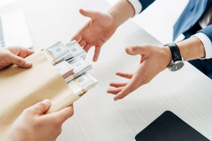 cropped view of man taking envelope with cash near business partner
